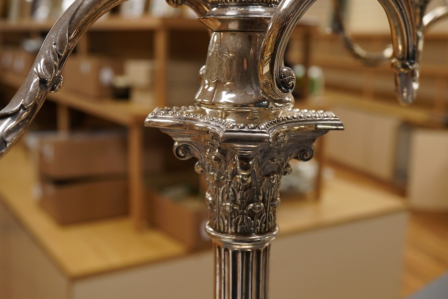 A garniture of 19th century silver plated Corinthian column candelabra, comprising a pair of two branch, three light candelabra and matching four branch, five light candelabrum, with detachable acanthus leaf capped scrol